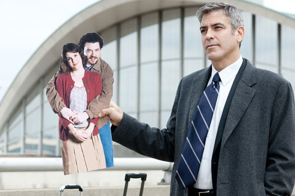 Ryan Bingham (George Clooney, far right) holds up a cardboard photo of his sister Julie (Melanie Lynskey, far left) and her fiancé Jim (Danny McBride, near left) in the dramatic comedy UP IN THE AIR, a Paramount Pictures release. Photo Credit: Dale Robinette. Copyright © 2009 DW STUDIOS L.L.C. and COLD SPRING PICTURES. All Rights Reserved.